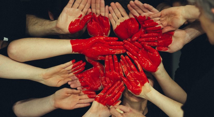 hands of many people joind with painted red heart shape